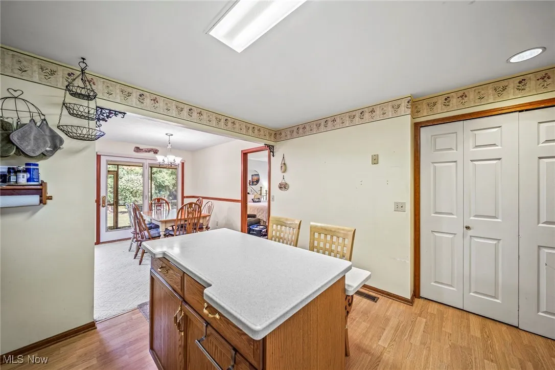 Kitchen with a kitchen island, light wood-style flooring, light countertops, brown cabinets, and pendant lighting