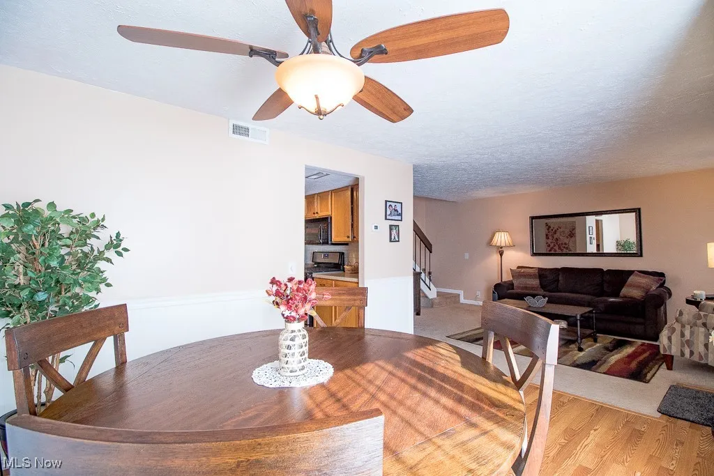 Dining area with light wood-style floors, ceiling fan, a textured ceiling, and stairs