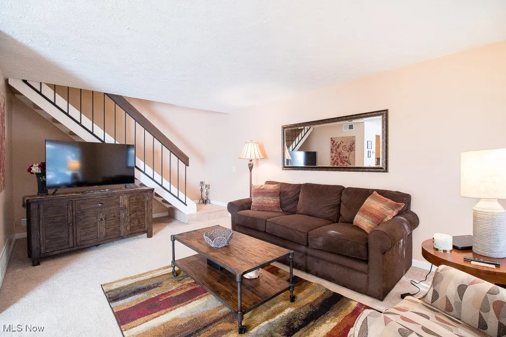 Carpeted living area with stairway and a textured ceiling