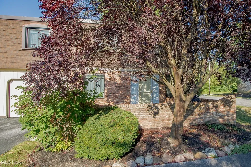 View of property hidden behind natural elements with brick siding