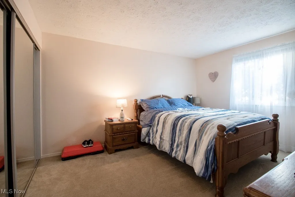 Bedroom with a textured ceiling, carpet floors, and a closet