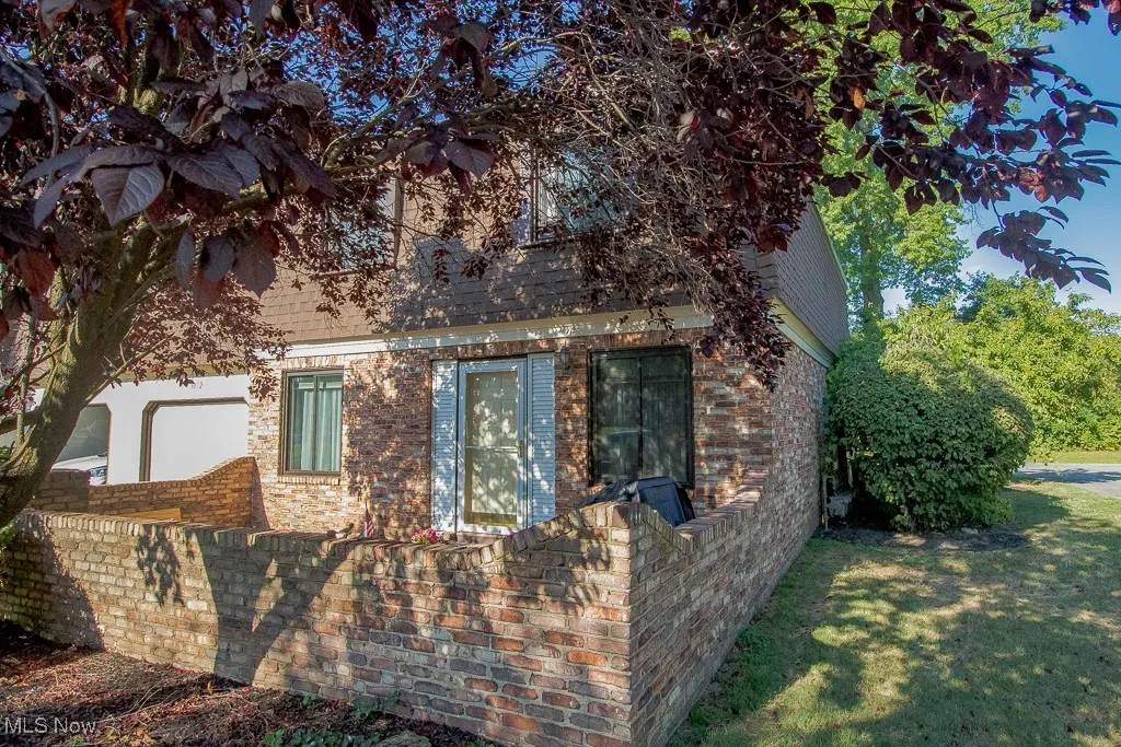 View of home's exterior featuring brick siding, a shingled roof, and a yard