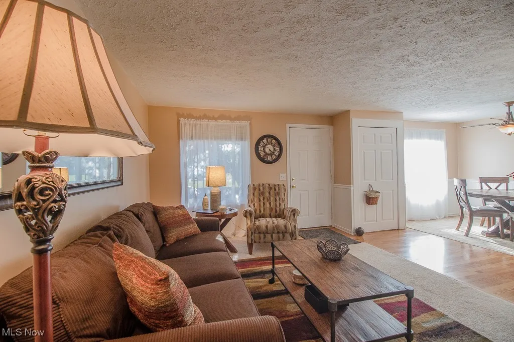 Living room with wood finished floors, a textured ceiling, and a ceiling fan