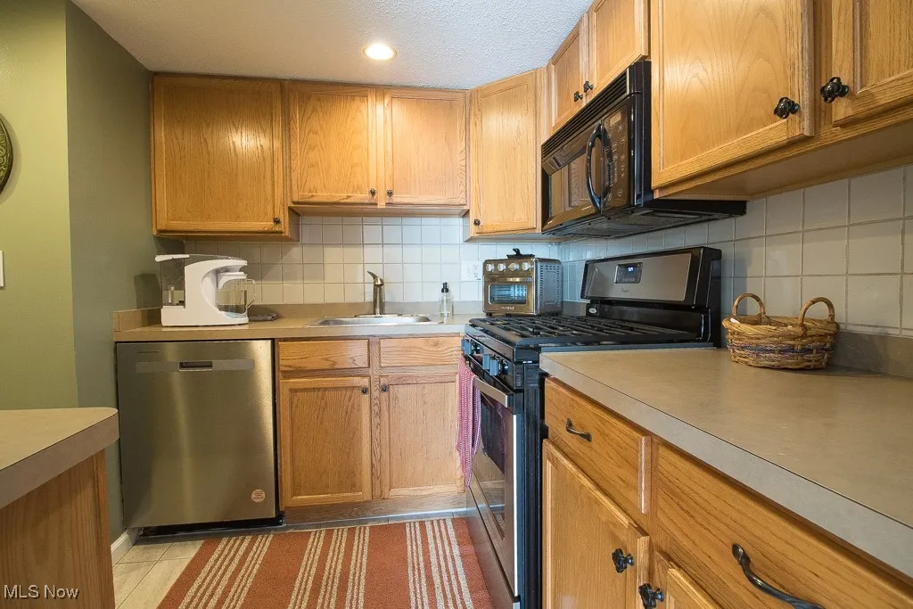 Kitchen featuring appliances with stainless steel finishes, tasteful backsplash, light countertops, brown cabinets, and recessed lighting
