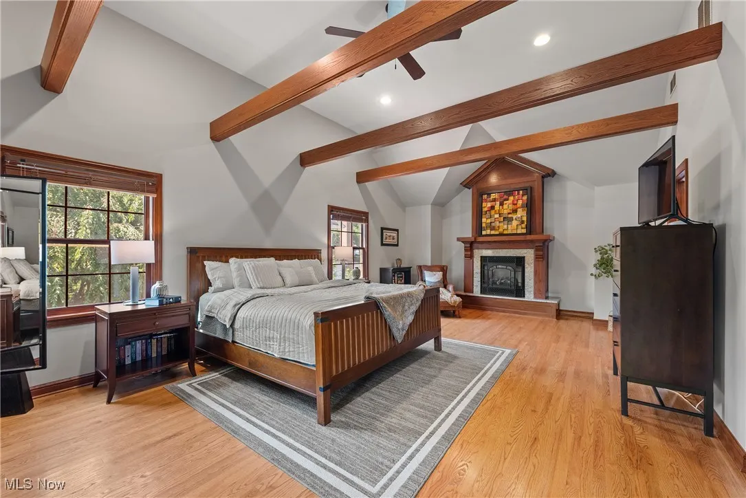 Bedroom with light wood finished floors, a large fireplace, and a ceiling fan