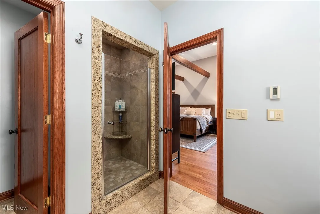 Full bathroom featuring a stall shower, light tile patterned floors, and connected bathroom