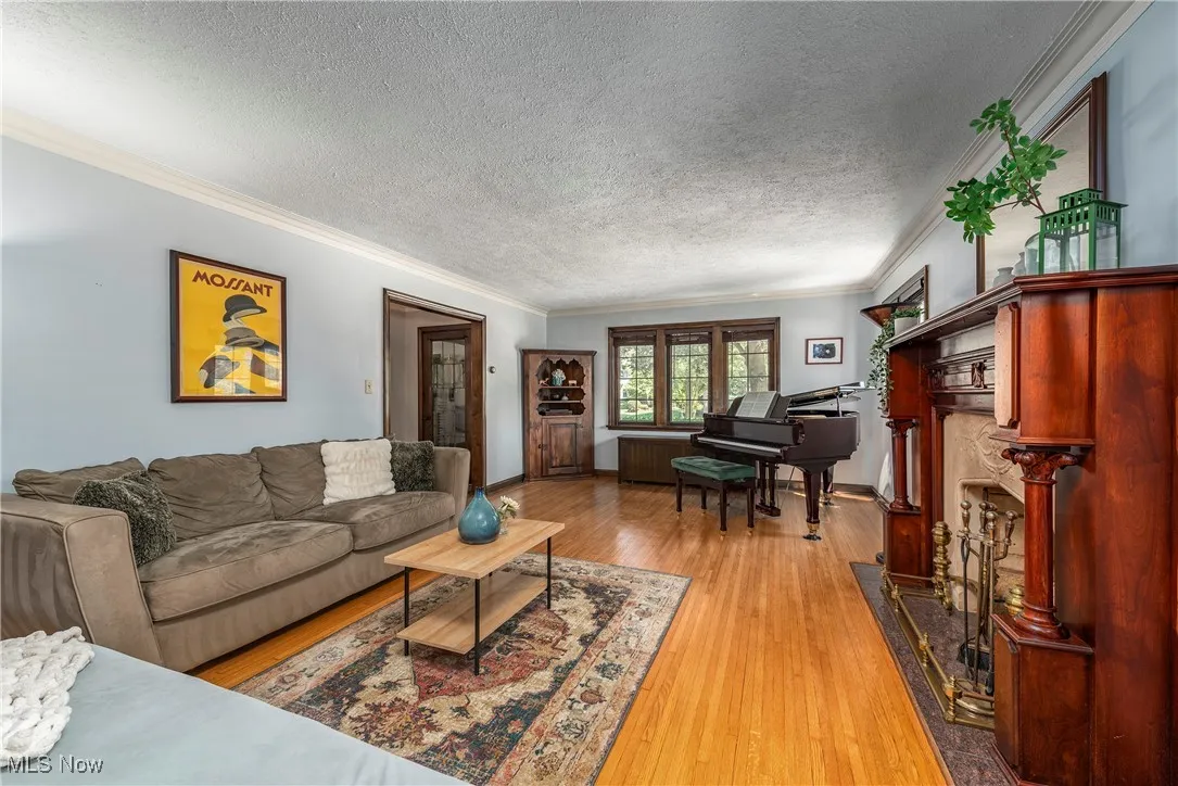 Living room with ornamental molding, light wood-type flooring, a textured ceiling, and a fireplace
