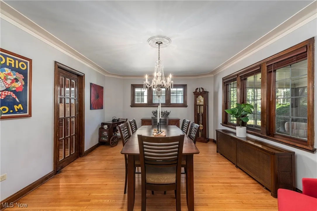 Dining space featuring light wood finished floors, a chandelier, ornamental molding, and radiator heating unit