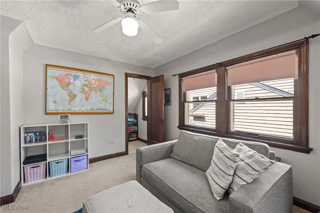 Living room featuring a textured ceiling, carpet flooring, and ceiling fan