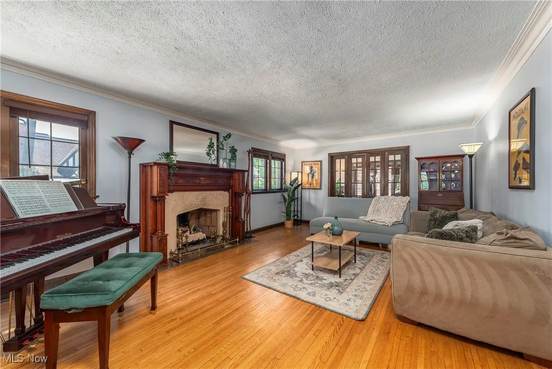 Living room with ornamental molding, wood-type flooring, a textured ceiling, and a fireplace