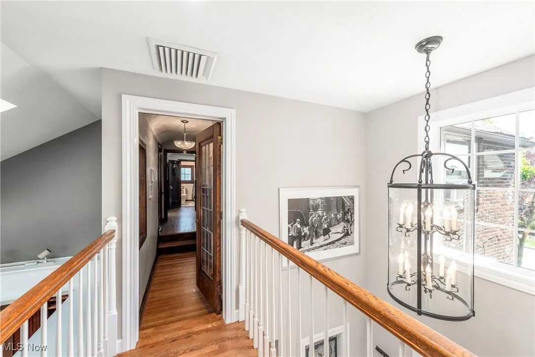 Hall featuring a chandelier, light wood-type flooring, an upstairs landing, and plenty of natural light