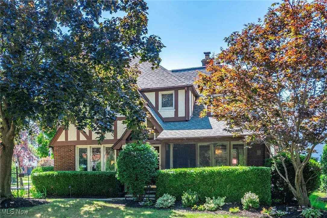 English style home featuring a shingled roof, stucco siding, a chimney, and brick siding