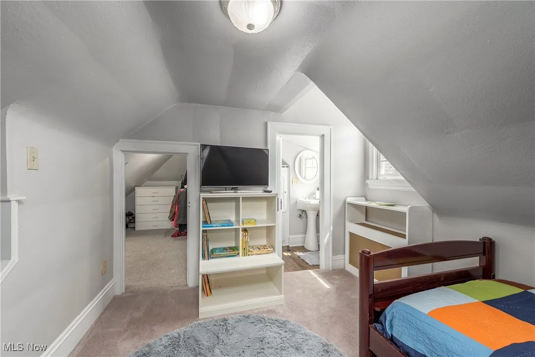 Bedroom with light colored carpet, a textured ceiling, lofted ceiling, and a spacious closet