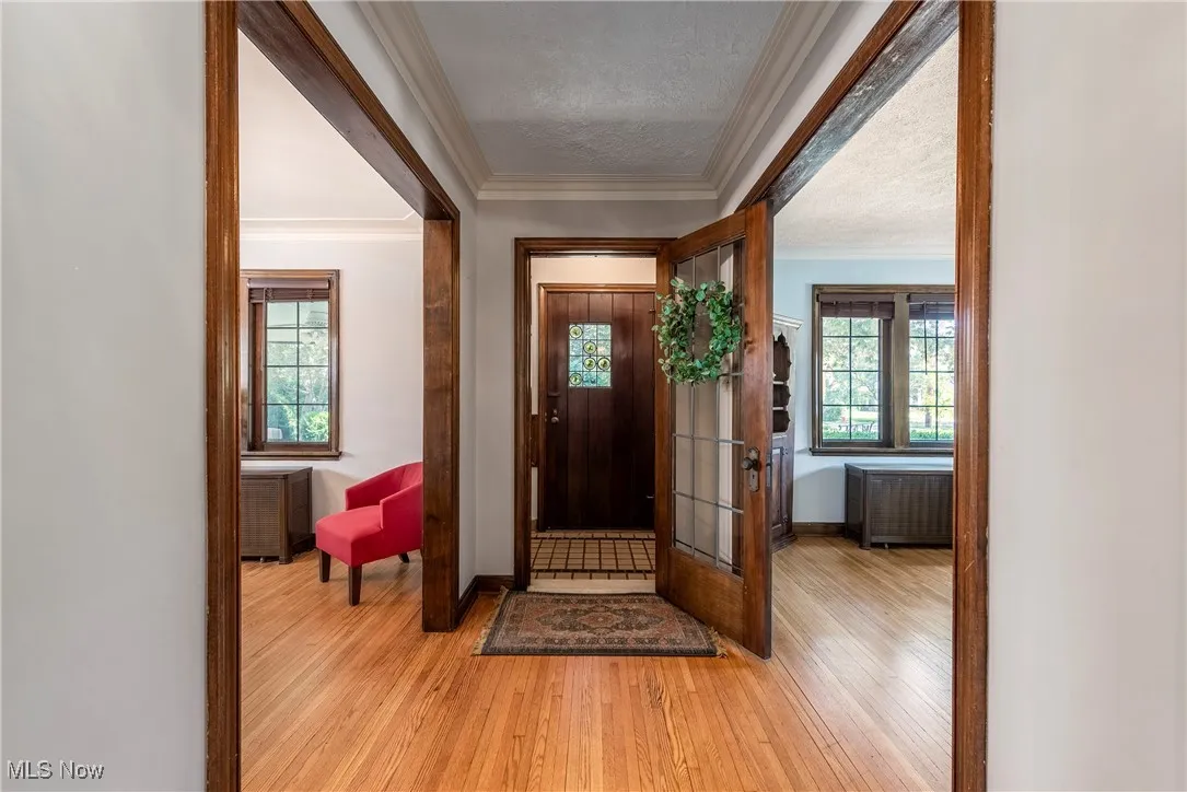 Entryway with ornamental molding, light wood finished floors, plenty of natural light, radiator heating unit, and a textured ceiling