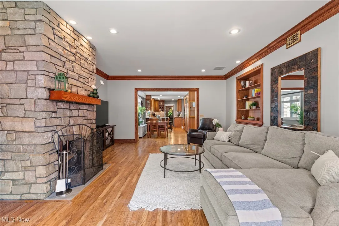 Living area with wood finished floors, ornamental molding, recessed lighting, and a fireplace