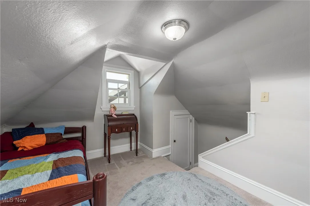 Bedroom with light carpet, a textured ceiling, and lofted ceiling