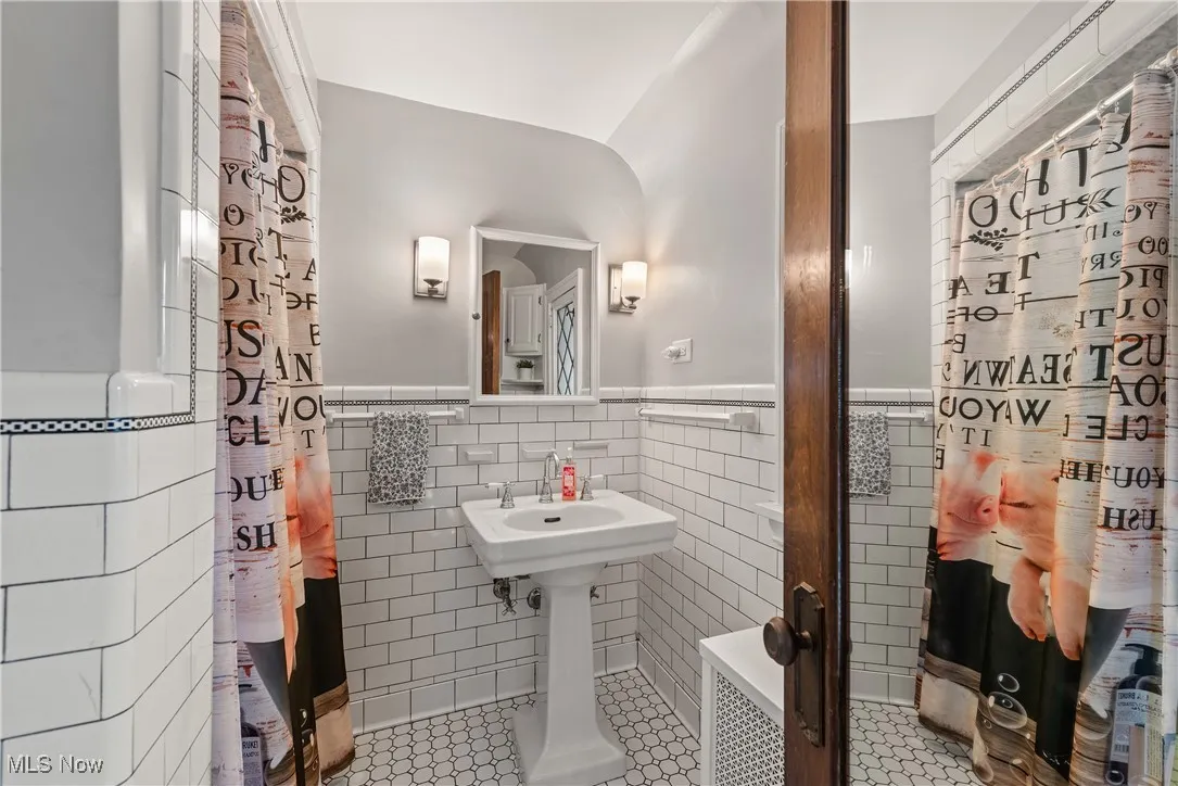 En-suite Bathroom featuring tile walls, tile patterned floors, and wainscoting