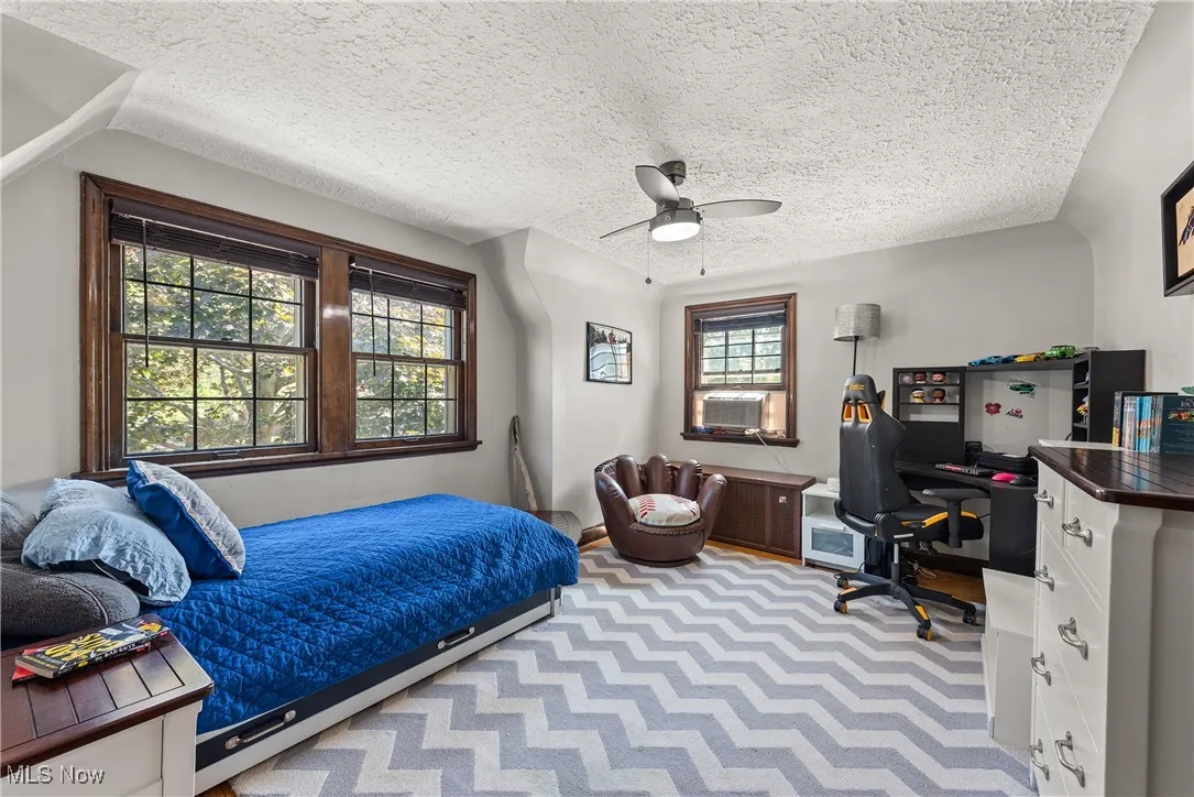 Bedroom featuring a desk, a textured ceiling, and a ceiling fan