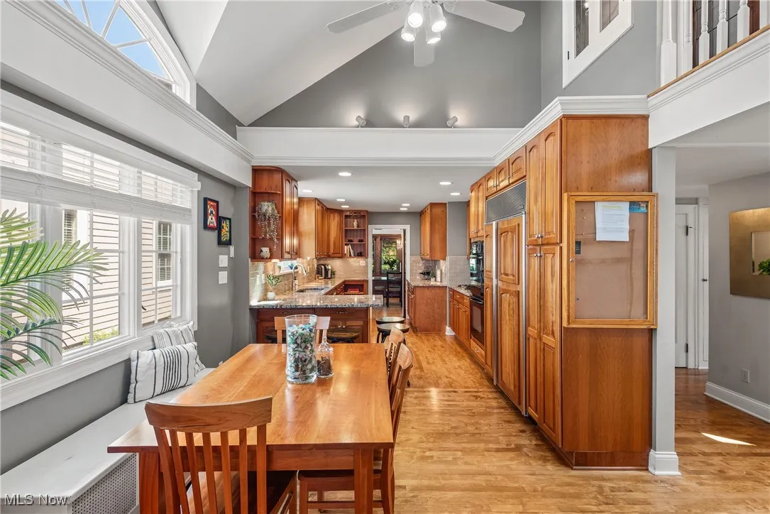 Dining room featuring light wood finished floors, high vaulted ceiling, and a ceiling fan
