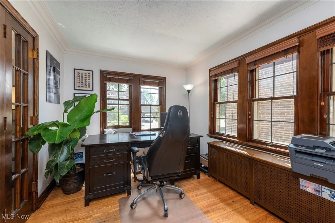 Home office featuring radiator heating unit, light wood-type flooring, ornamental molding, and a textured ceiling