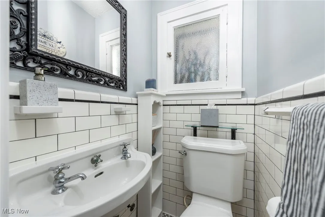 Half bathroom with tile walls and wainscoting