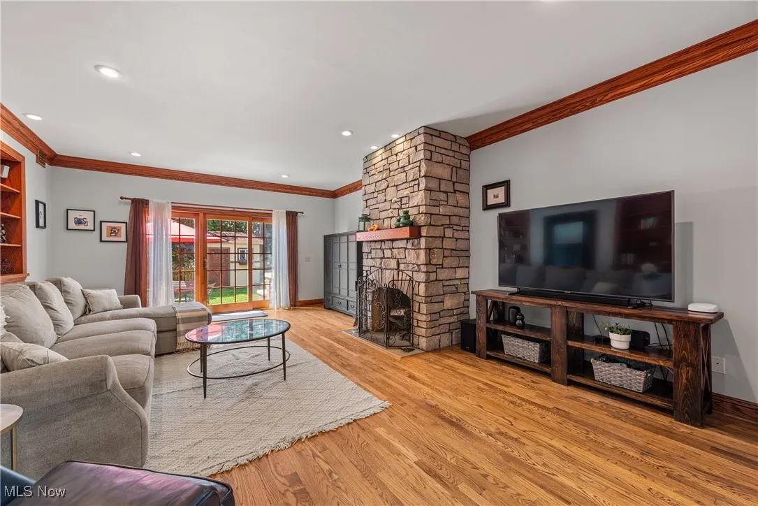 Living room featuring ornamental molding, a fireplace, light wood-style floors, and recessed lighting