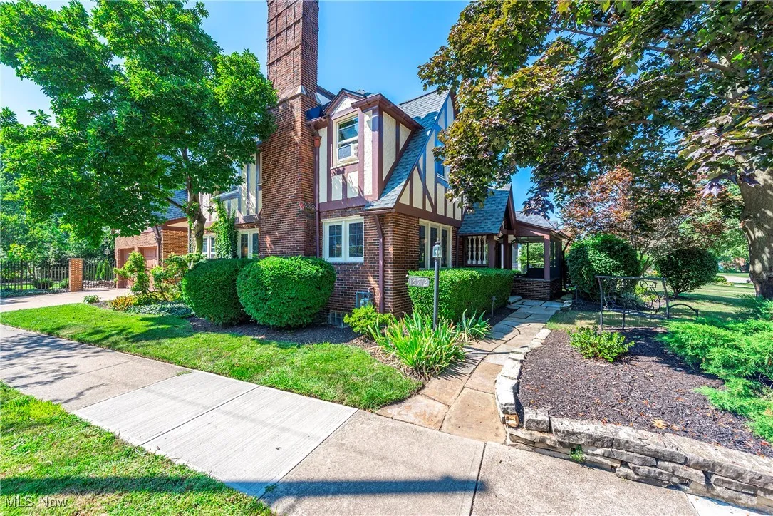 View of property exterior featuring a chimney, brick siding, a yard, and stucco siding