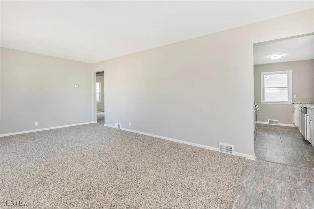Empty room with light colored carpet and plenty of natural light