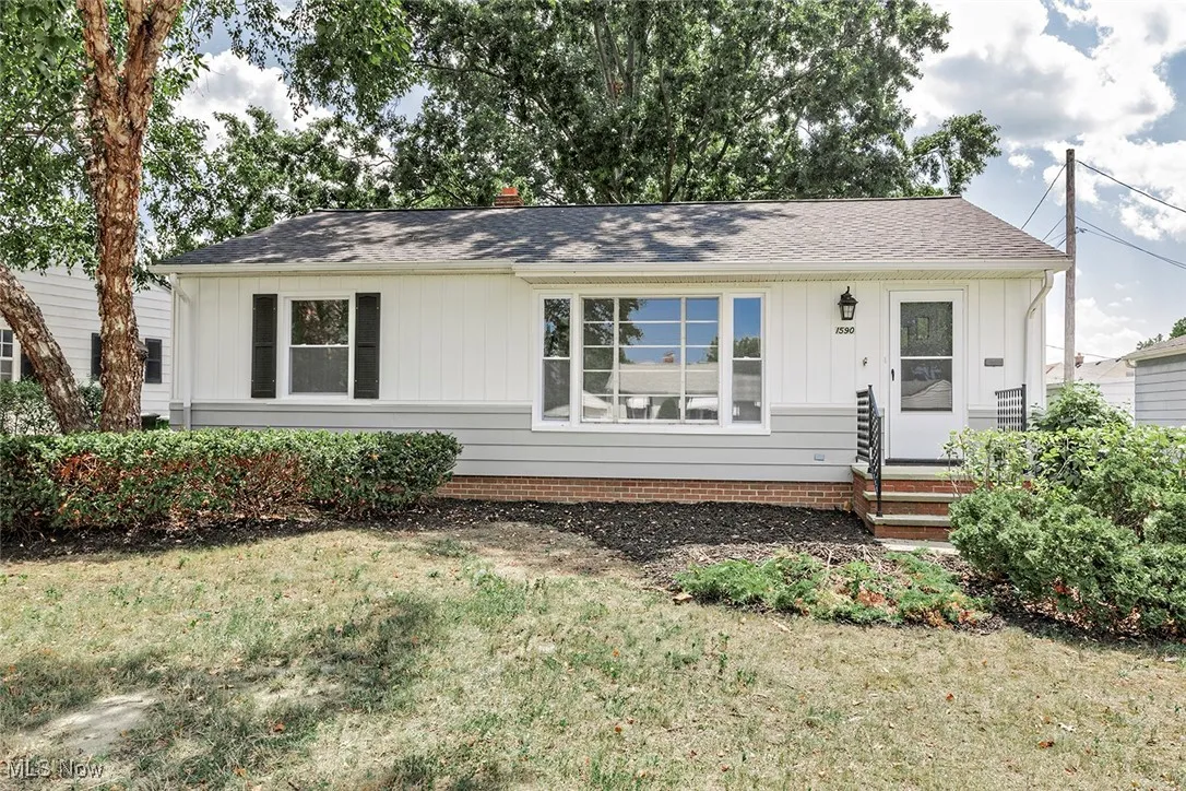 View of front of home featuring board and batten siding, roof with shingles, and a front lawn