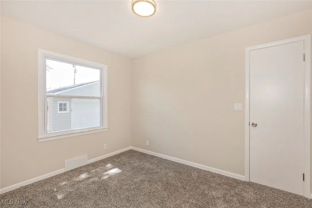 Carpeted spare room featuring baseboards