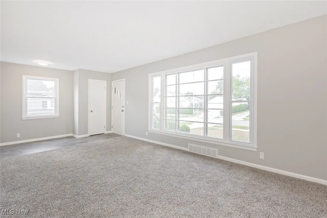 Unfurnished living room featuring baseboards and carpet