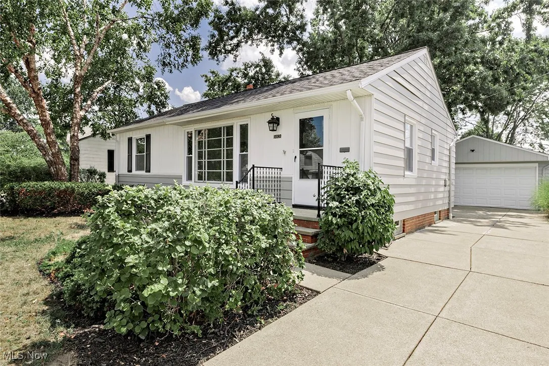 View of front of home featuring a detached garage, an outdoor structure, roof with shingles, and crawl space