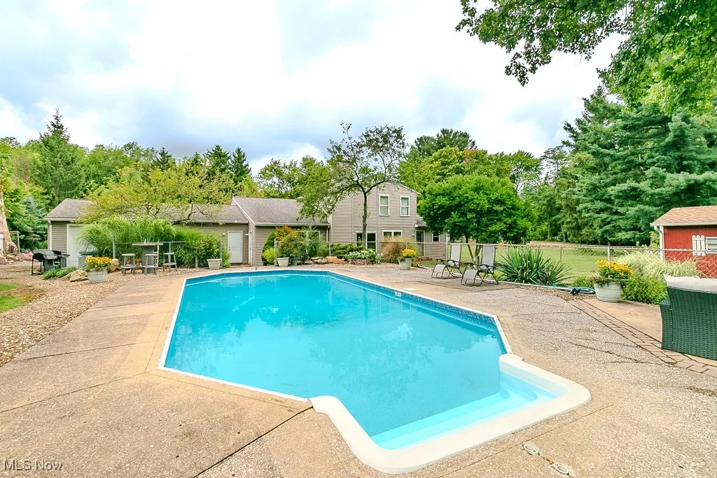 View of pool featuring a patio and view of scattered trees