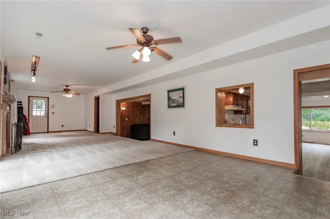 Unfurnished living room with ceiling fan and baseboards