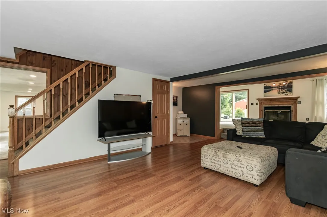 Living area with light wood finished floors, a glass covered fireplace, and stairs