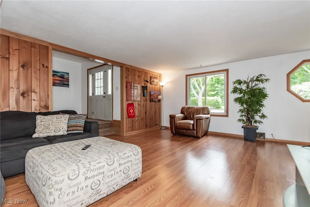 Living area with wooden walls, light wood-style flooring, and plenty of natural light