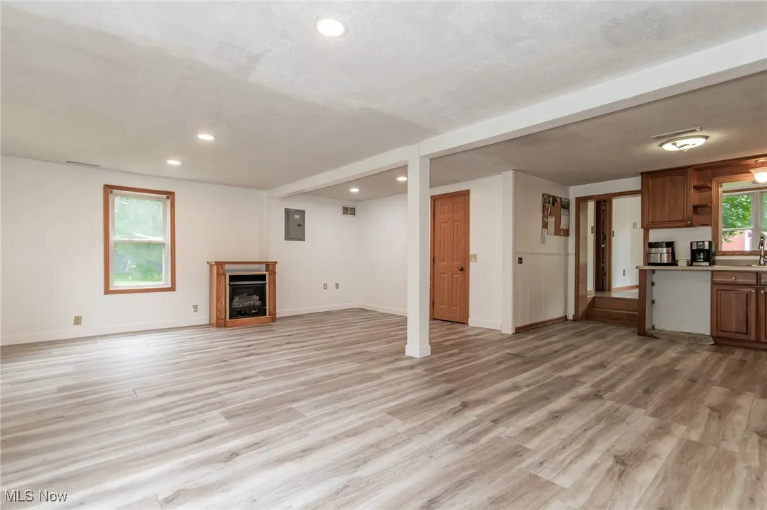 Unfurnished living room featuring recessed lighting, a fireplace, light wood-style flooring, and electric panel