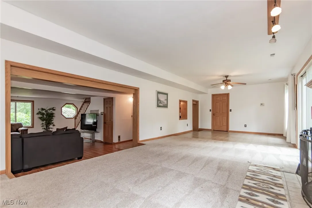 Unfurnished living room with light carpet and ceiling fan