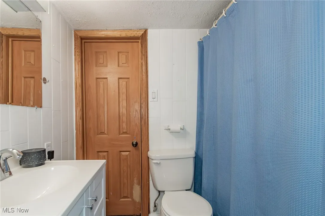Bathroom featuring a textured ceiling, vanity, and a shower with shower curtain