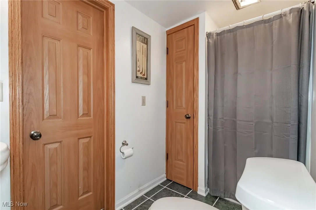 Full bathroom with dark tile patterned floors and curtained shower