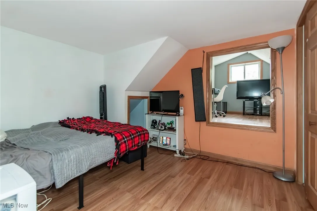 Bedroom with wood finished floors and lofted ceiling