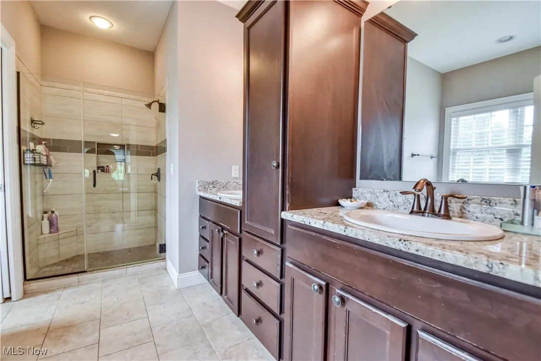 Primary bath with walk in closet, glass shower, and double vanities