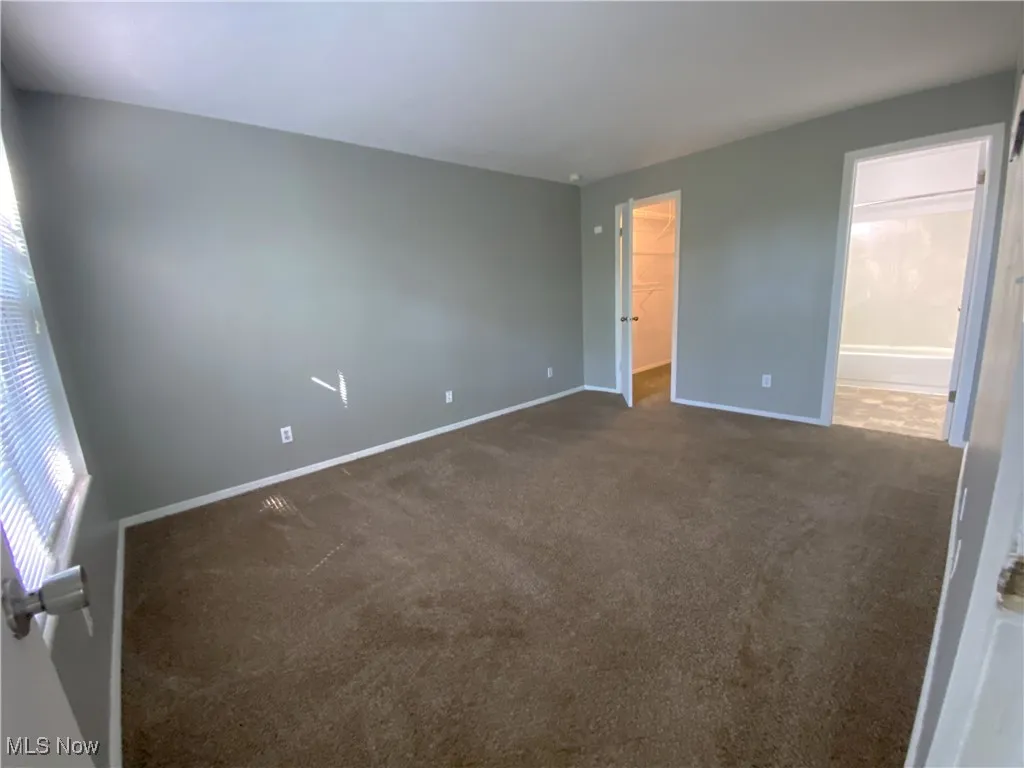 Main bedroom with ensuite bath, large walk in closet and carpeted floor.