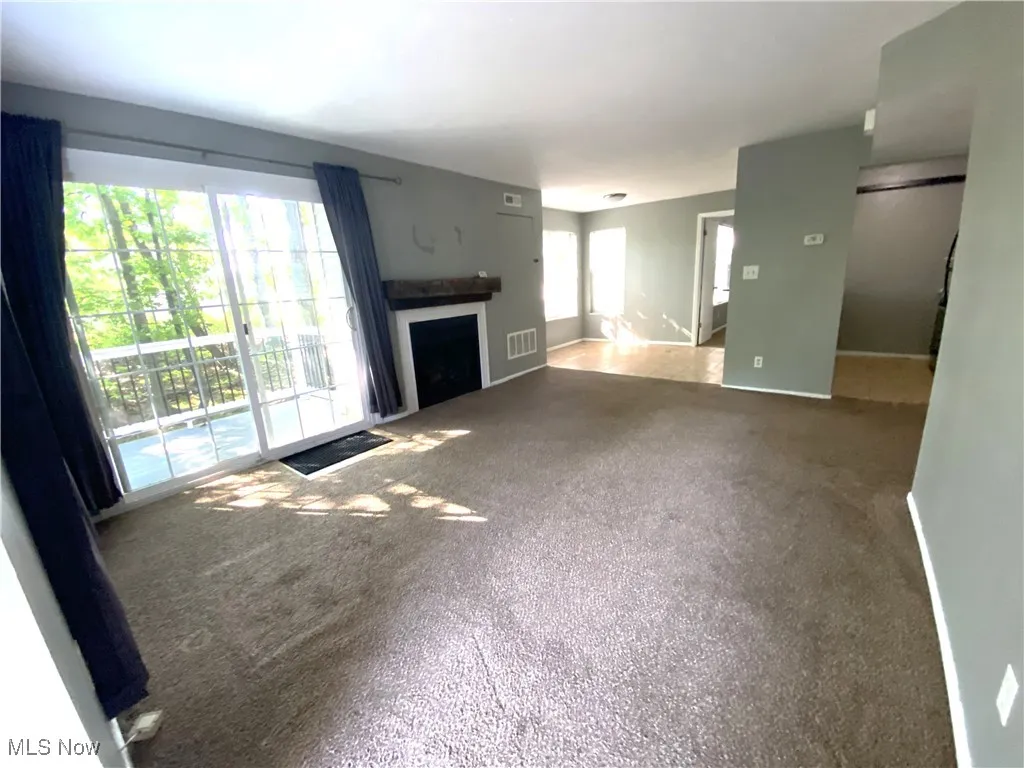 Living room with carpeted floors, fireplace, patio doors to deck, and opens to dining area