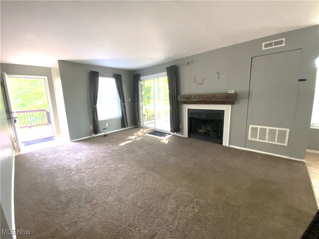 Living room with carpet, fireplace and patio doors to deck