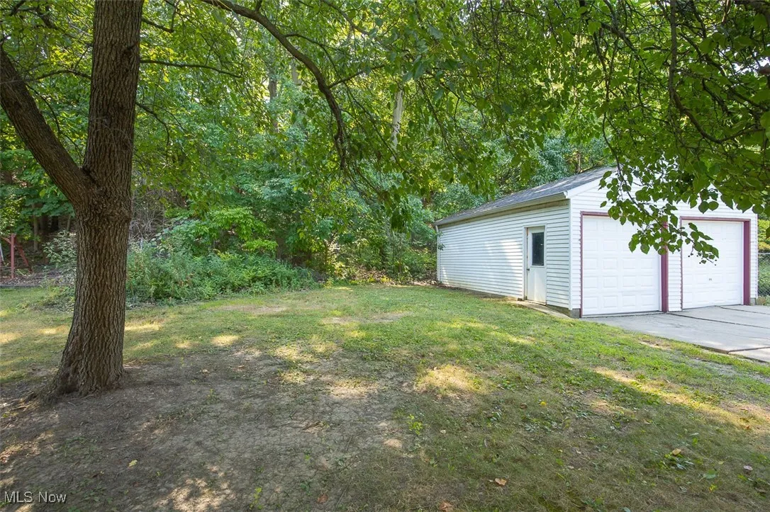 View of green lawn with an outbuilding and a garage