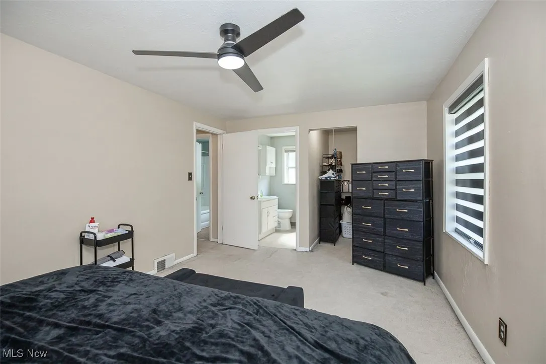 Bedroom featuring light carpet, a ceiling fan, and ensuite bathroom