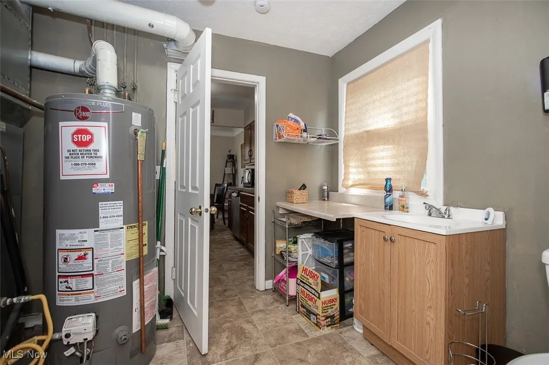 Utility room featuring water heater and a sink