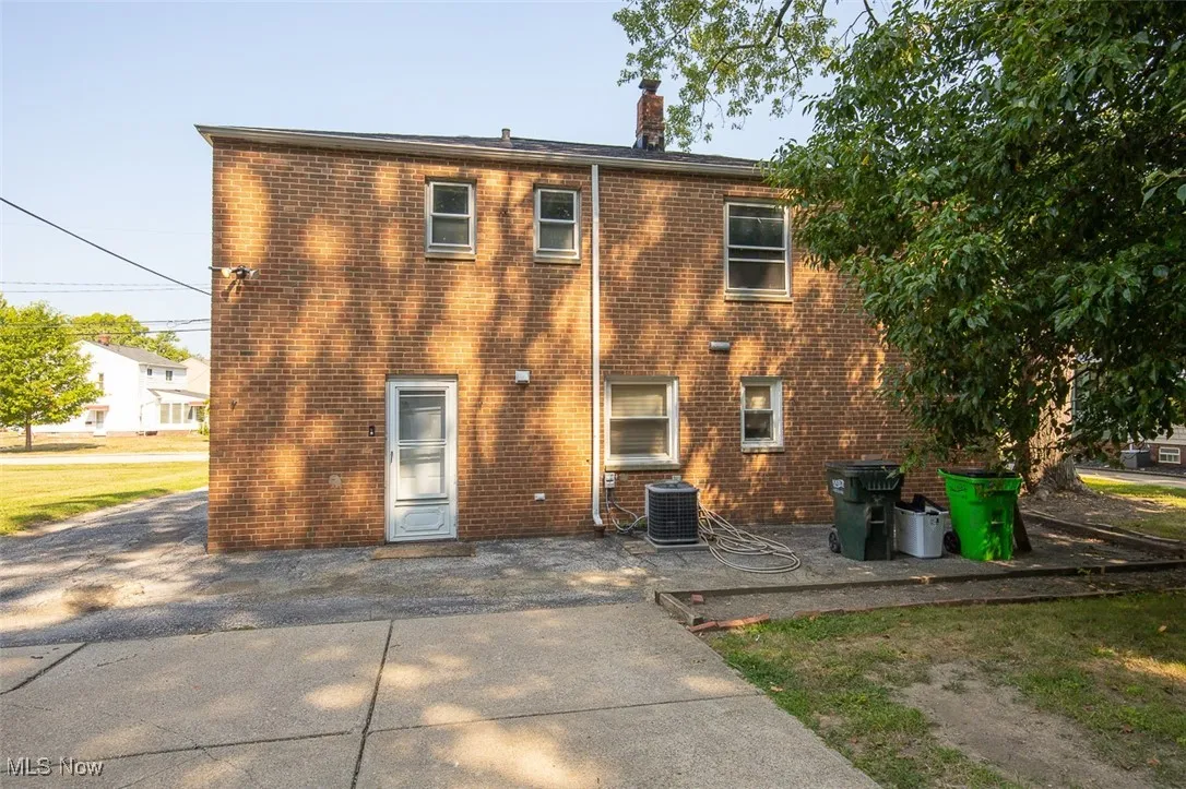 Rear view of property with a chimney, brick siding, and a patio area