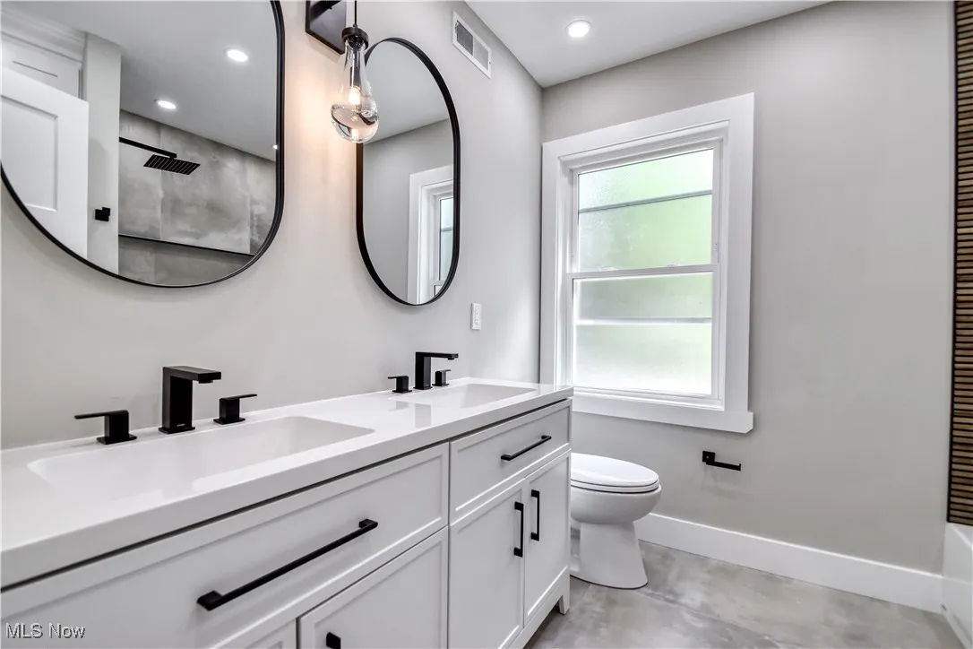 Bathroom featuring double vanity, a shower, recessed lighting, and concrete floors